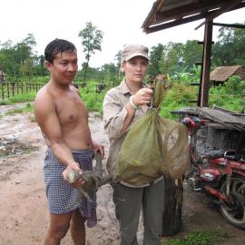 Two people hold aloft lizard monitors confiscated from traders